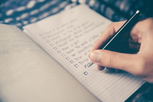 A notebook, with someone writing tasks